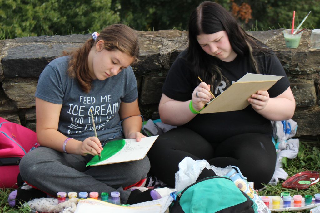 Moundsville Middle School students Peyton McBroom and Serinity Blanton paint Moundsville’s cityscape from high atop the mound.