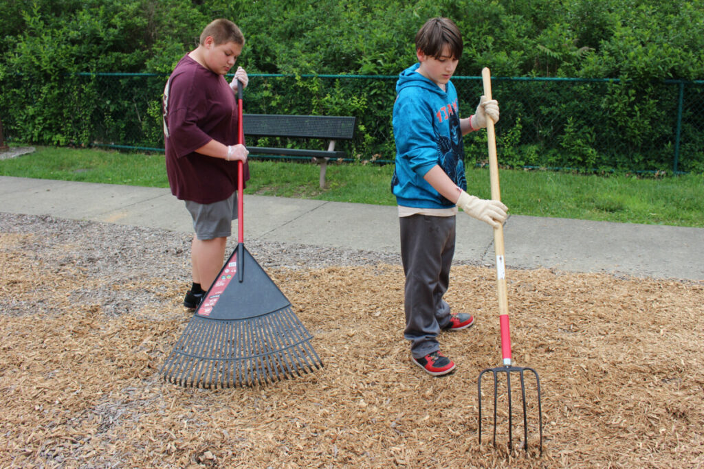 Students spread mulch at Grand Vue's playground.