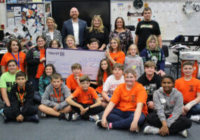 Members of the Evan G. Roberts Trust committee are presenting Sue Lewicki and her band students with an oversized check.